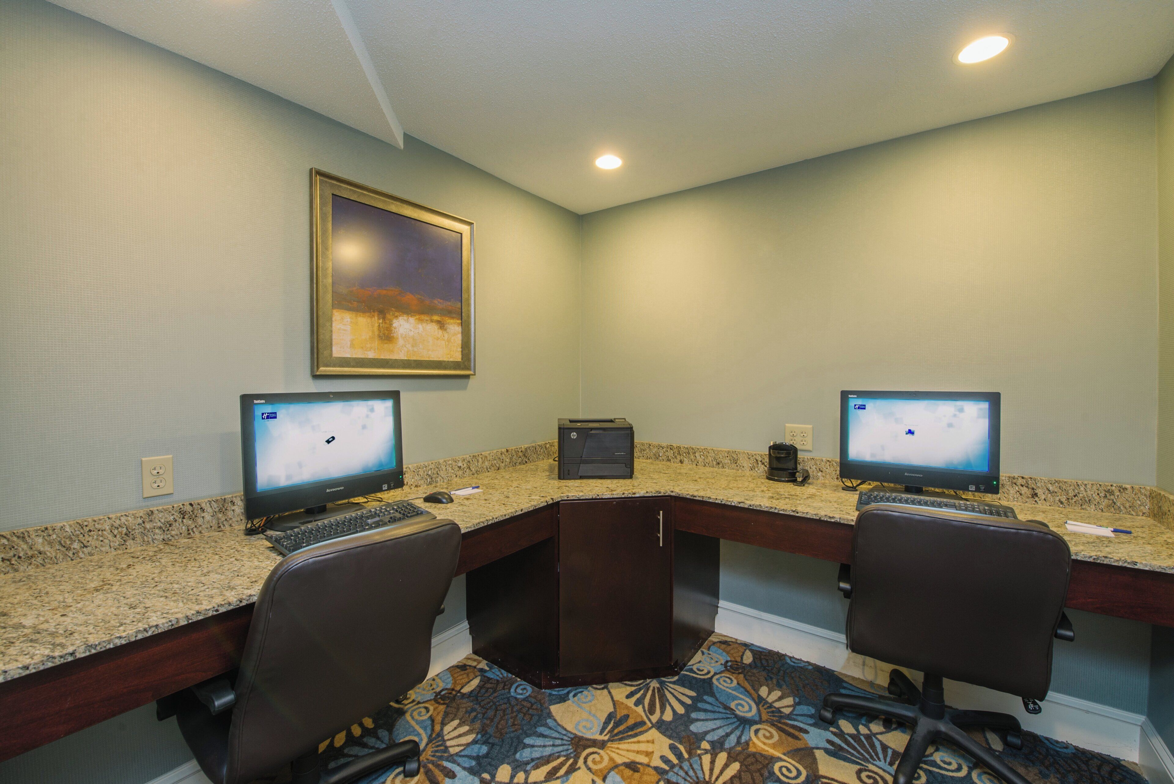A conference room with two desks, each with a computer, a printer, and a chair.