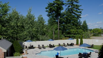 Una piscina al aire libre, sillones reclinables de piscina