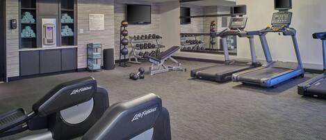 A gym with treadmills, a bench, dumbbells, and a water dispenser.