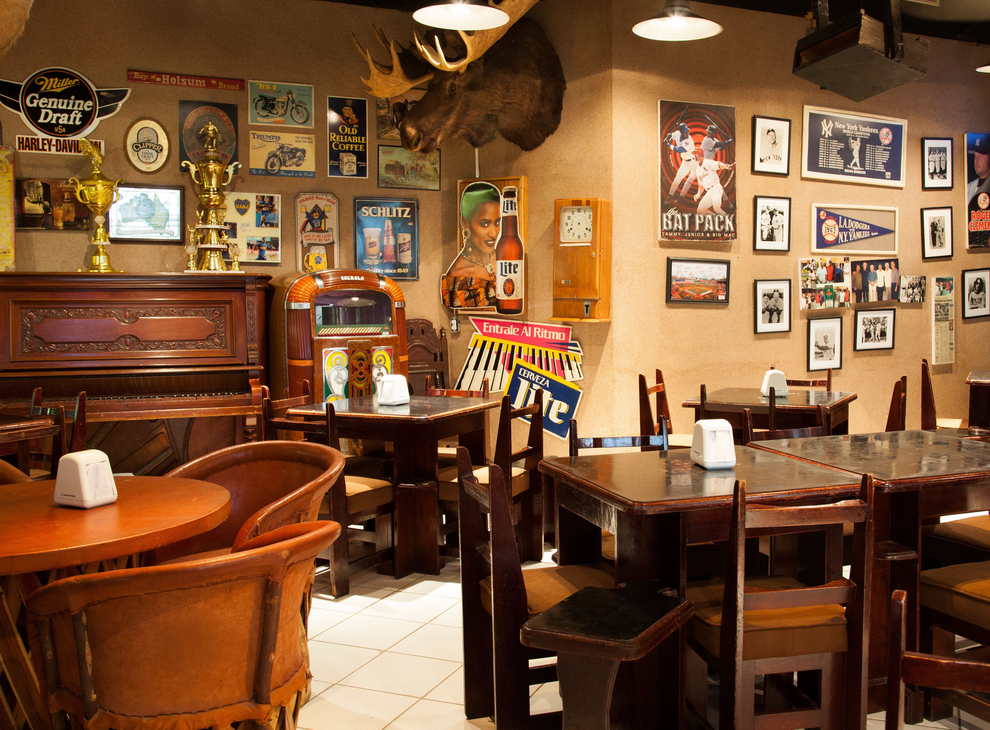Una zona de bar con mobiliario de madera, carteles antiguos y una decoración con cabeza de alce.