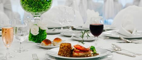 Une table à manger élégante, recouverte d’une nappe blanche, agrémentée de verres et d’un centre de table composé de fleurs blanches.