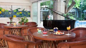 A restaurant with round tables and leather chairs, a piano, and a mural of lemons. - Viva Villahermosa (Villahermosa)