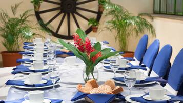 A table set for a formal dining event with white plates, blue napkins, and a centerpiece of red flowers.