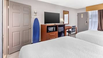 A hotel room with two beds, a desk with a TV, a microwave, a chair, and a door.