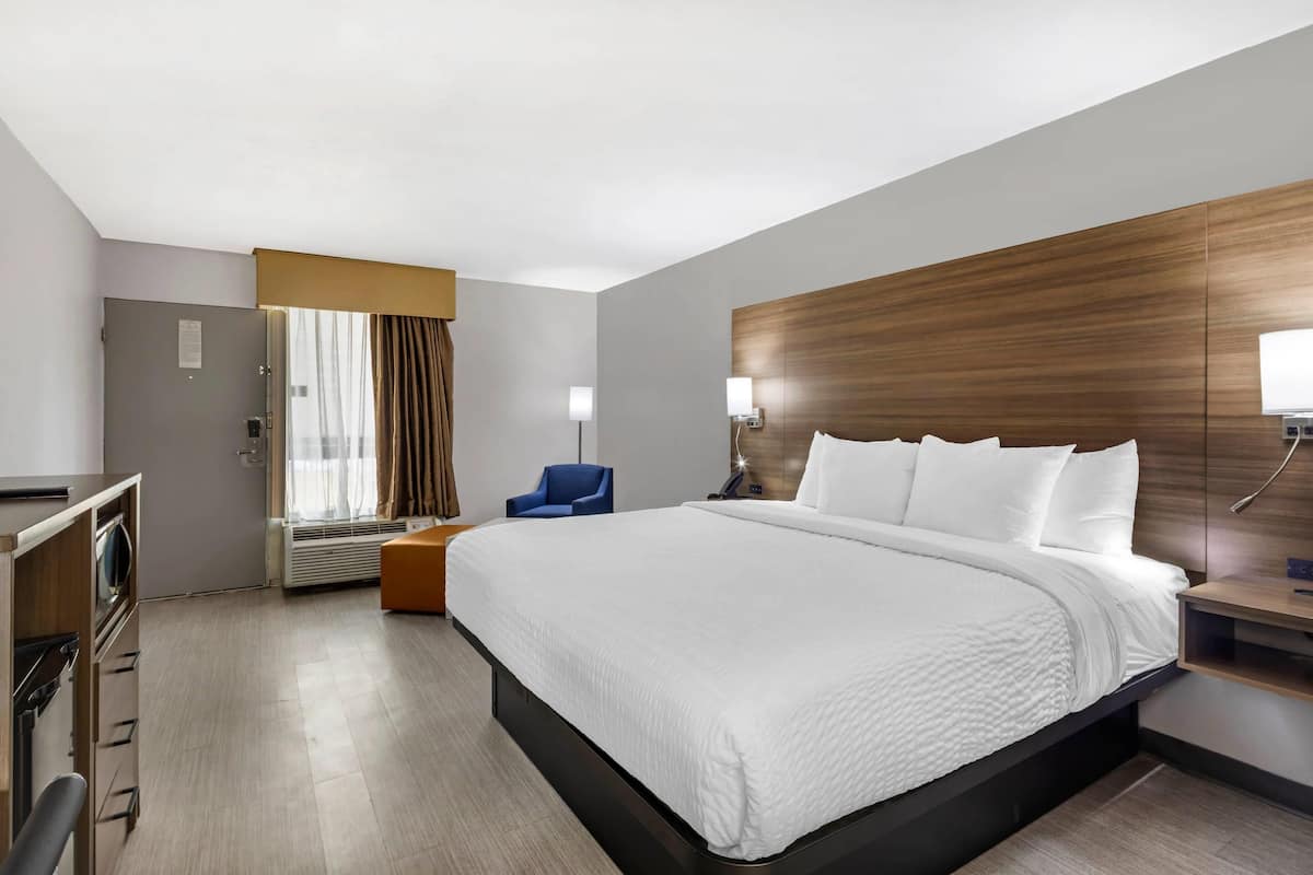 Una habitación de hotel con una cama grande, un escritorio, una silla y una ventana con cortinas.