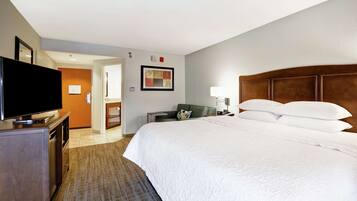 A hotel room with a large bed, a flat-screen TV, a desk, and a chair.