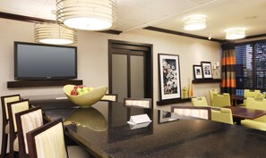 Un salón de conferencias de hotel con una gran mesa, sillas, una televisión y obras de arte en las paredes.