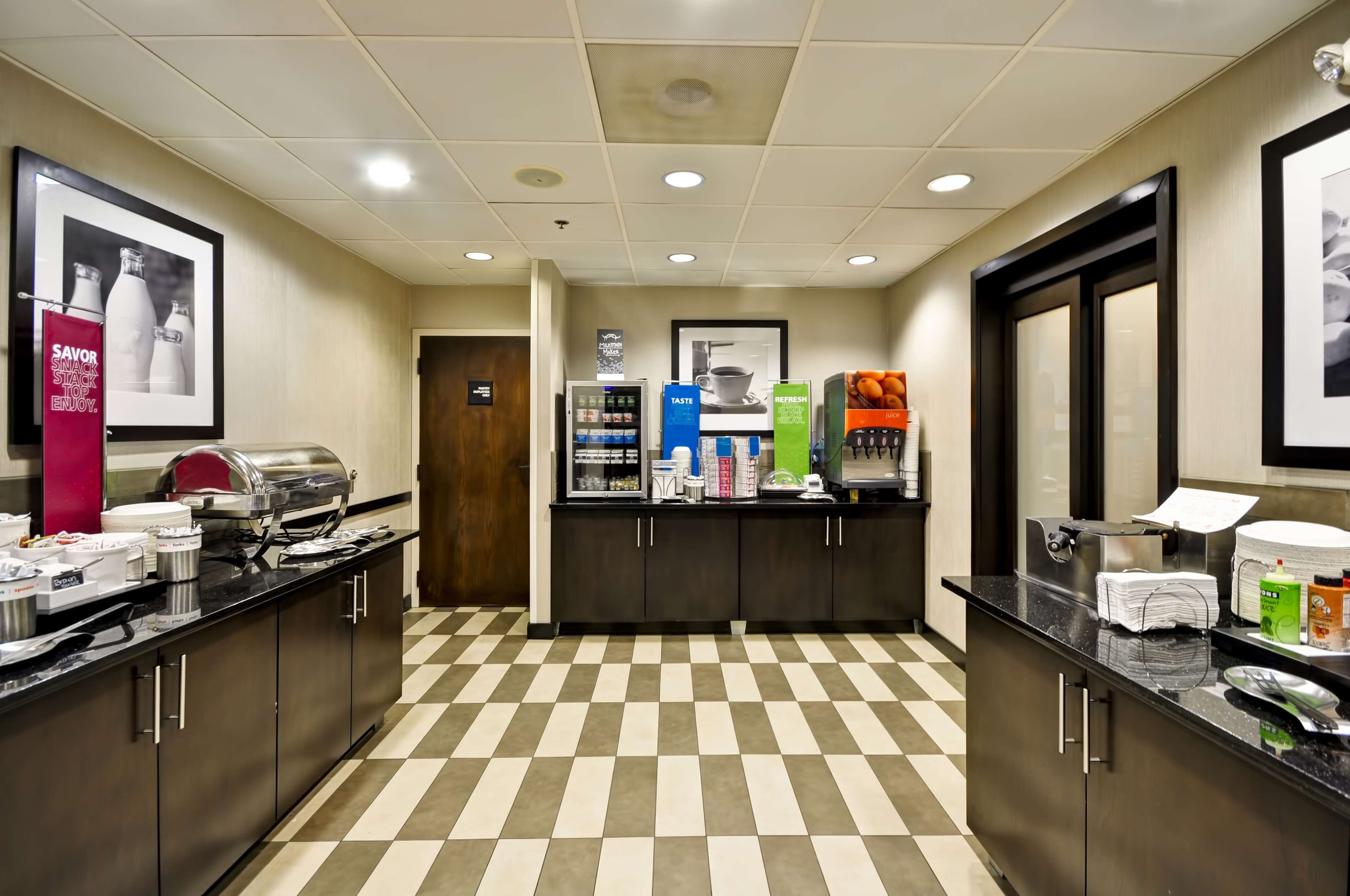 A hotel kitchen with a checkered floor, stainless steel appliances, and various food service items.