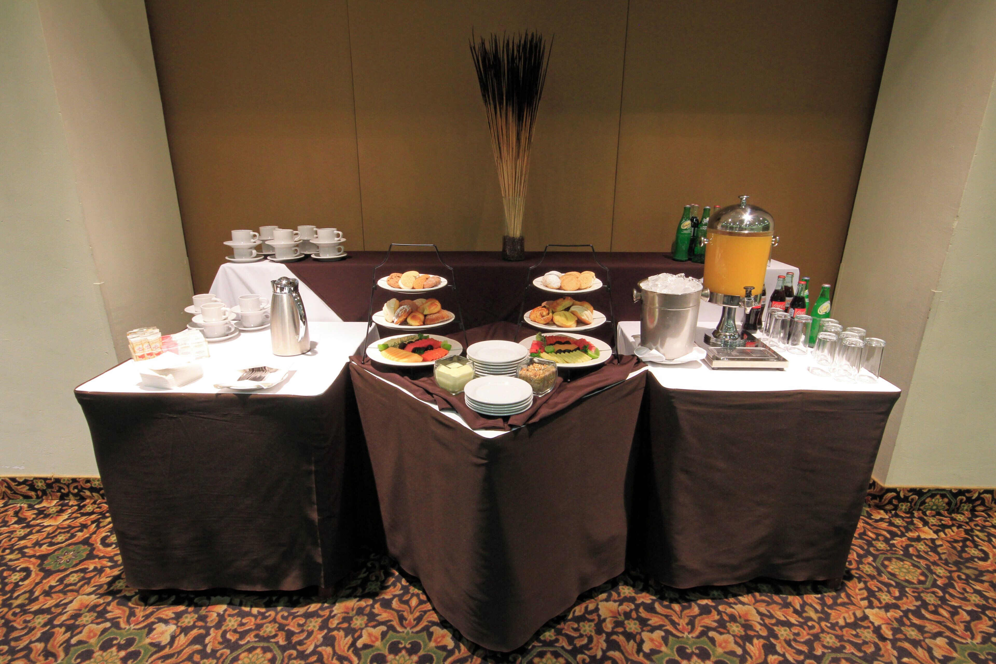 Ein Buffet mit mehreren Servierstationen, darunter Speisenplatten, eine Kaffeekanne und ein Getränkespender.