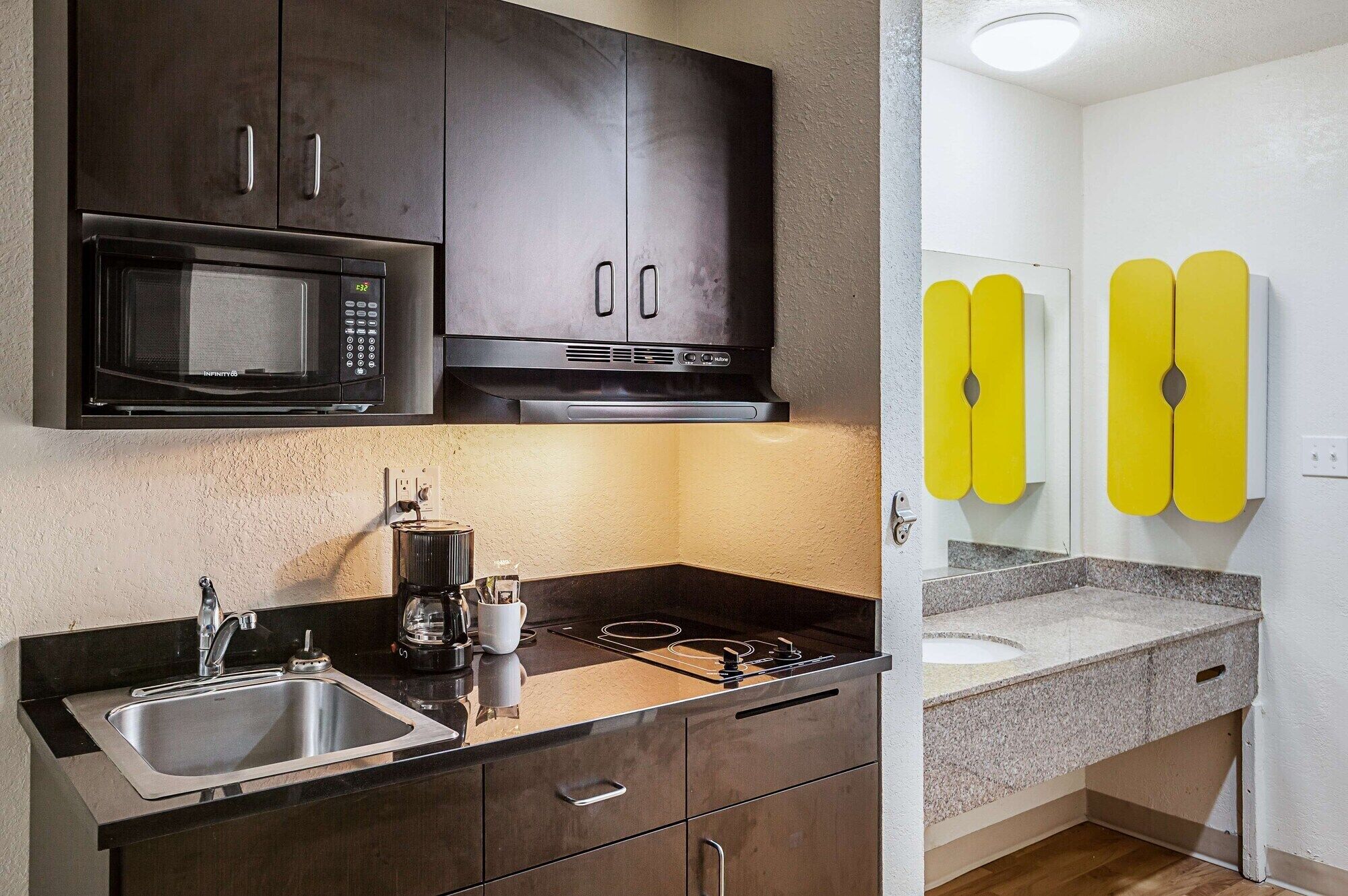 Cocina compacta con microondas, estufa y lavamanos.