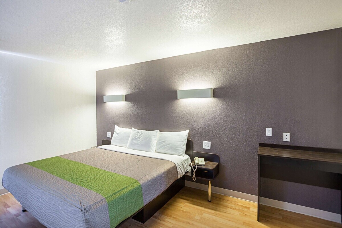 Une chambre d’hôtel moderne avec un grand lit, deux lampes de chevet, un téléphone sur la table de chevet et une petite table d’appoint en bois.