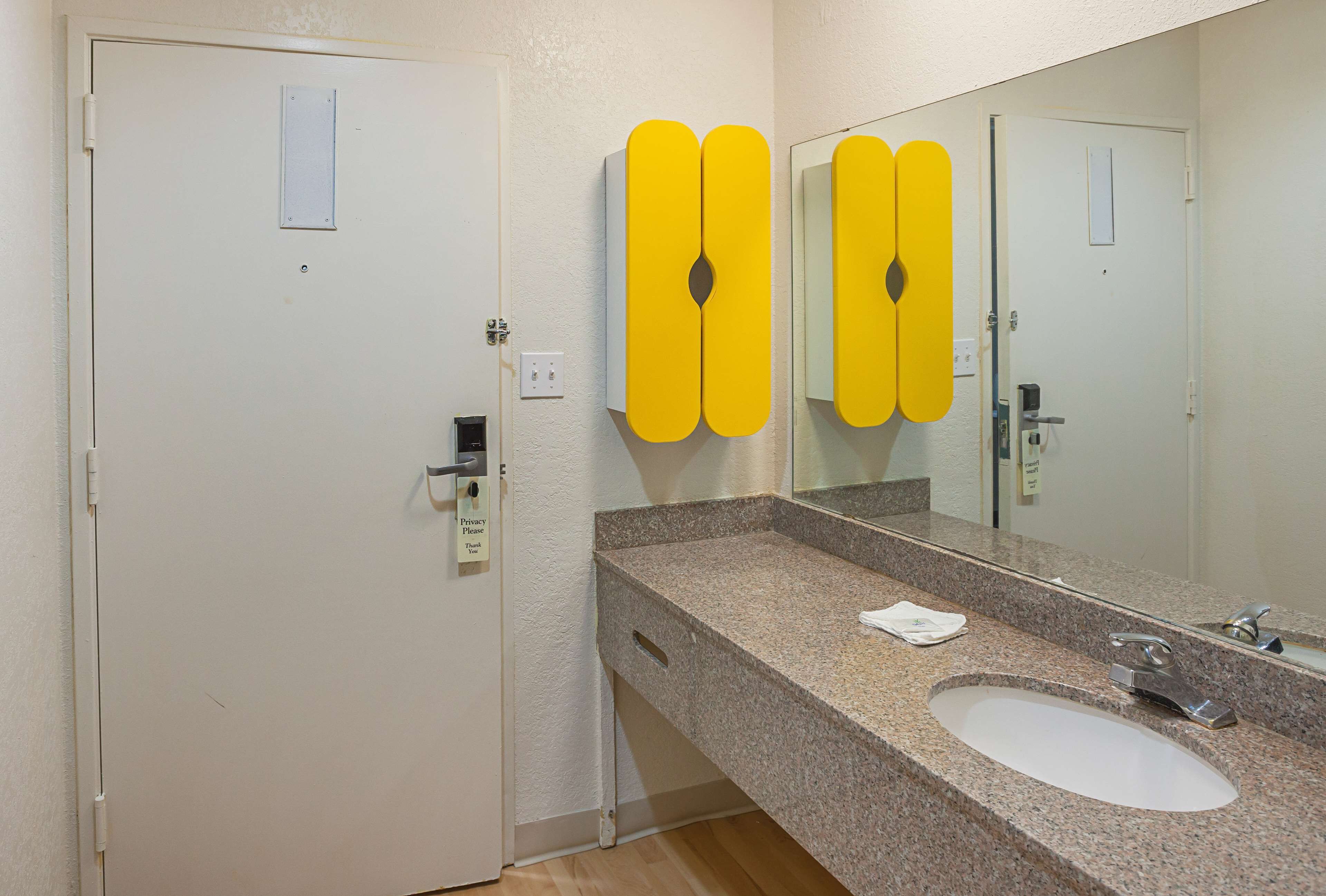 A bathroom with a granite countertop, a white sink, and a mirror.