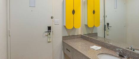 A bathroom with a granite countertop, a white sink, and a mirror.