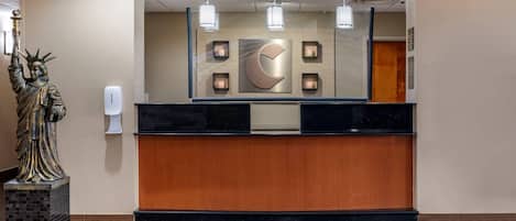 A reception desk with a large mirror, a statue, and a wall-mounted crescent moon design.