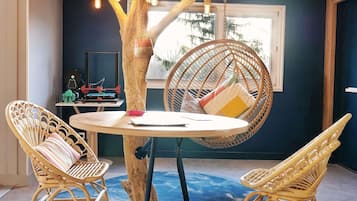 Relax in this inviting room with a central table, two wicker chairs, and a unique tree-shaped light fixture.