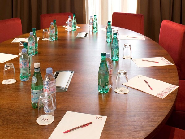 Una mesa de conferencias con botellas de agua, vasos y tarjetas de identificación en una sala de reuniones.