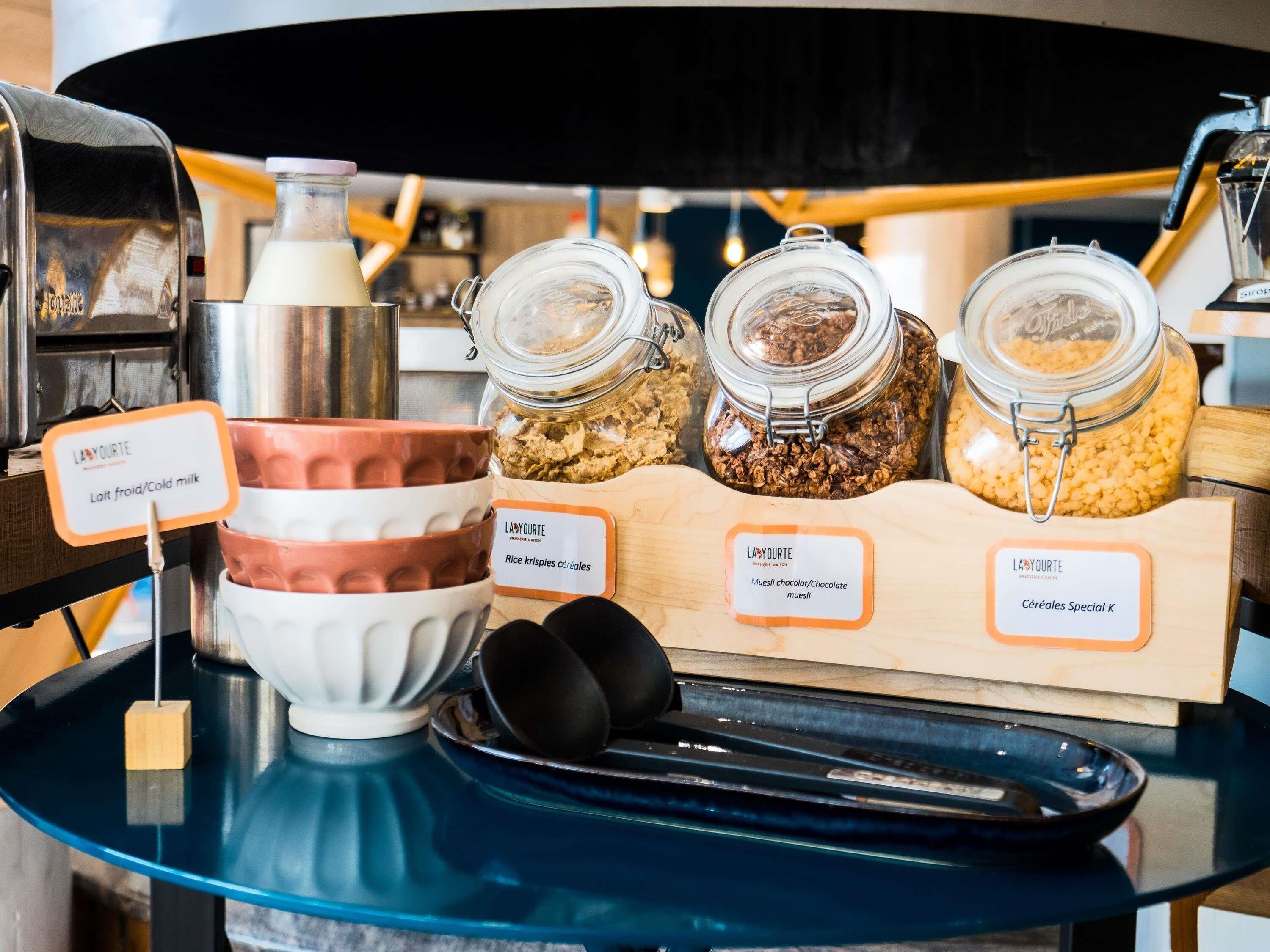 A breakfast buffet setup with labeled food items including cold milk, rice krispies cereal, chocolate/muesli, and special cereal K.