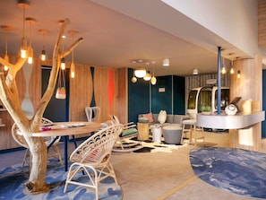A modern interior with a dining area, seating, a reception desk, and a unique tree-like light fixture. - Mercure Annemasse Porte de Genève (Gaillard)