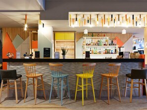 A bar area with wooden chairs, a counter with bottles, and a modern light fixture.