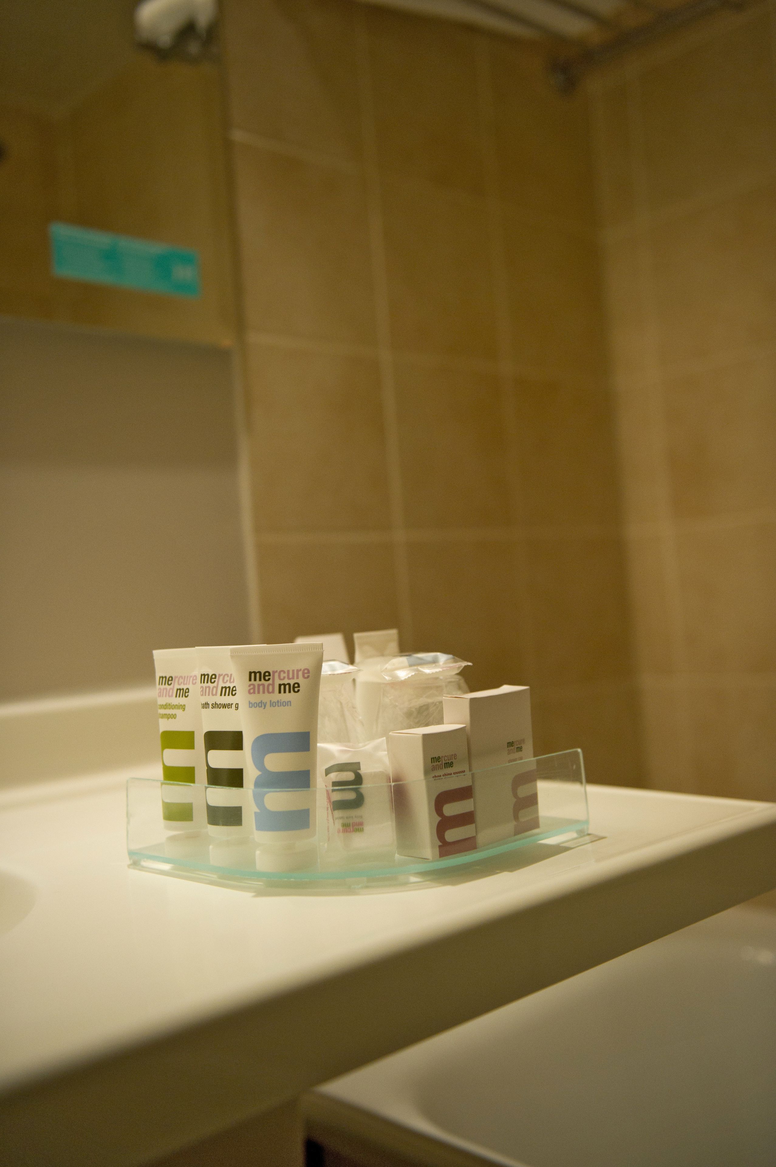 Ein Badezimmer mit Waschbecken und Pflegeprodukten auf einer Glasablage.