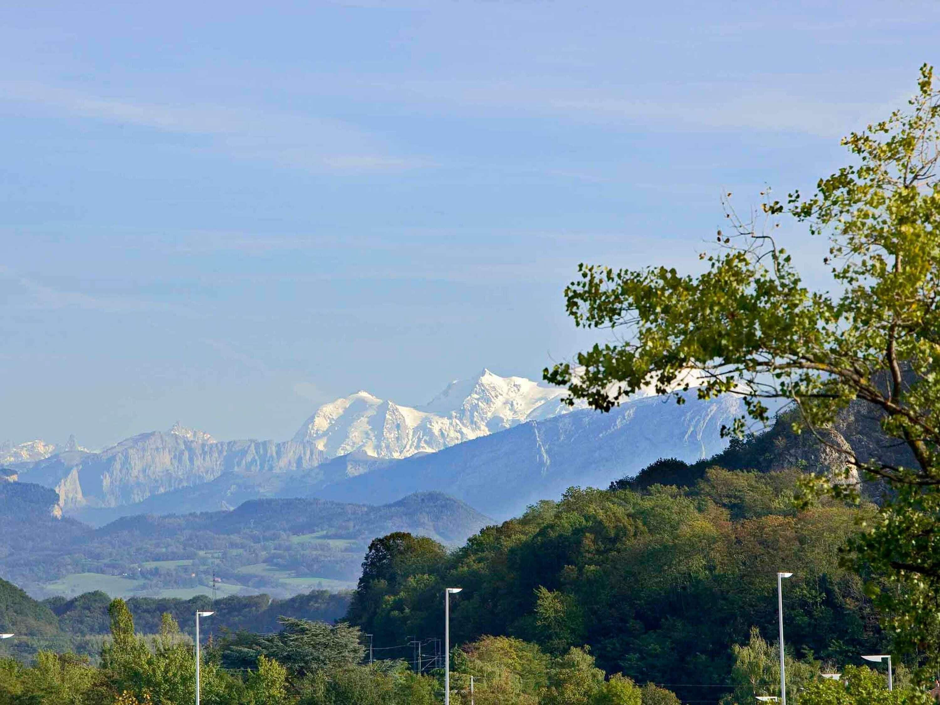 A mountainous landscape with snow-capped peaks, lush greenery, and street lamps.