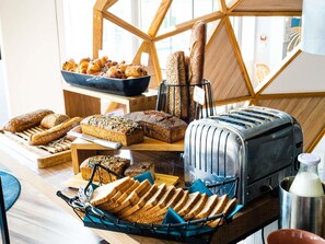 Um buffet de café da manhã com pães, doces e uma torradeira.