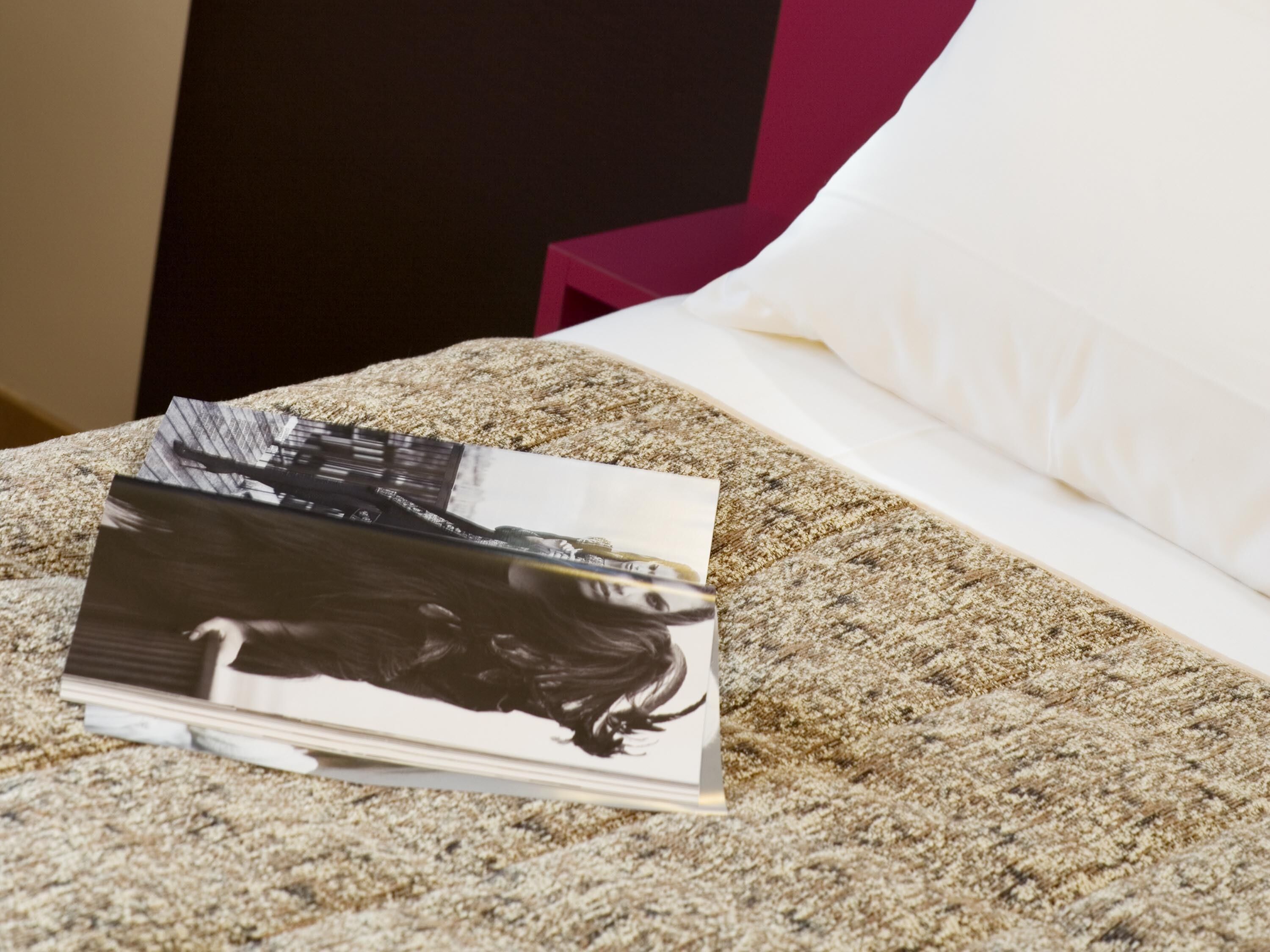 A bed with a textured blanket, a white pillow, and a magazine on it.