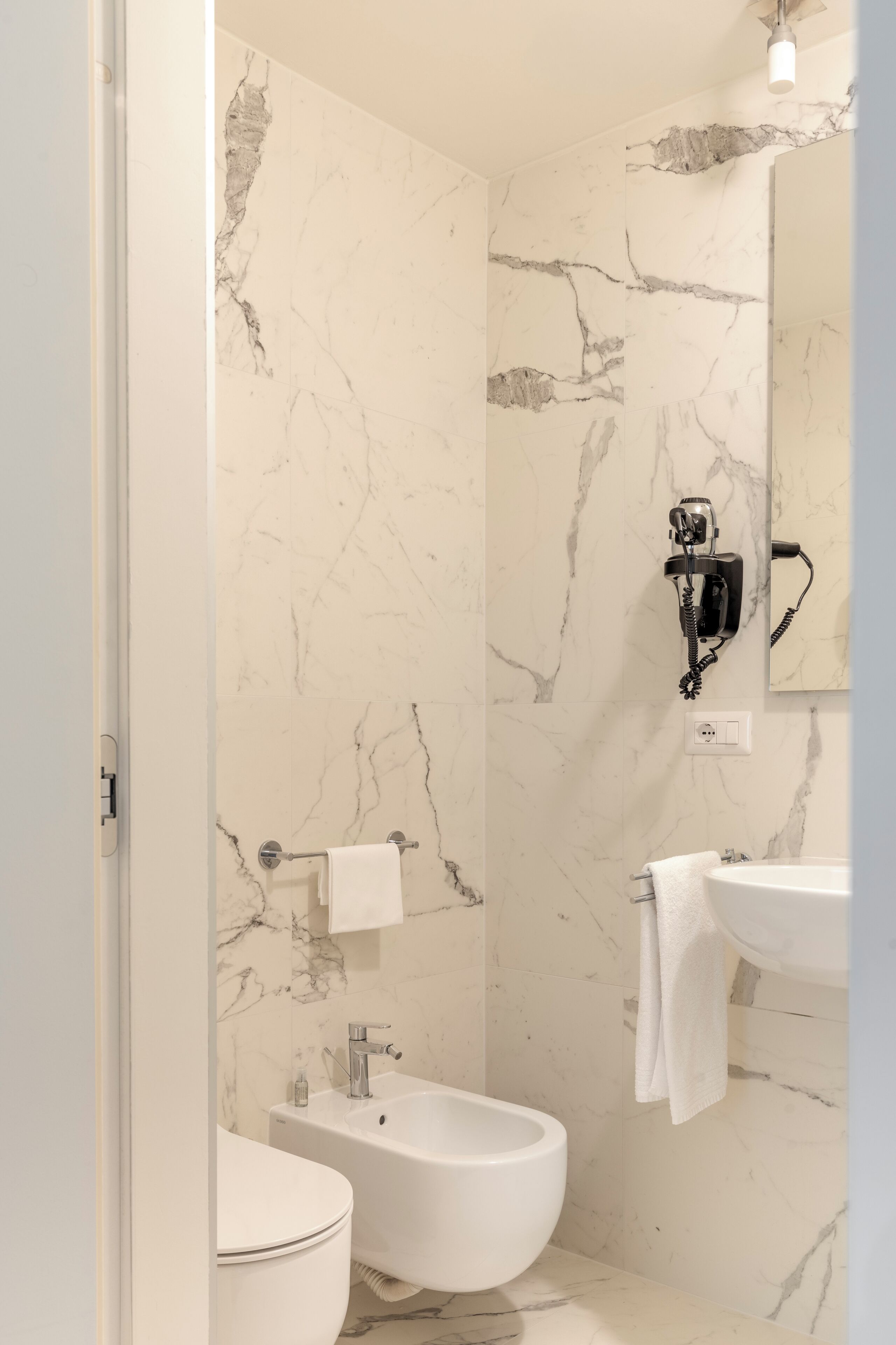 A bathroom with a toilet, bidet, and sink, all in white.