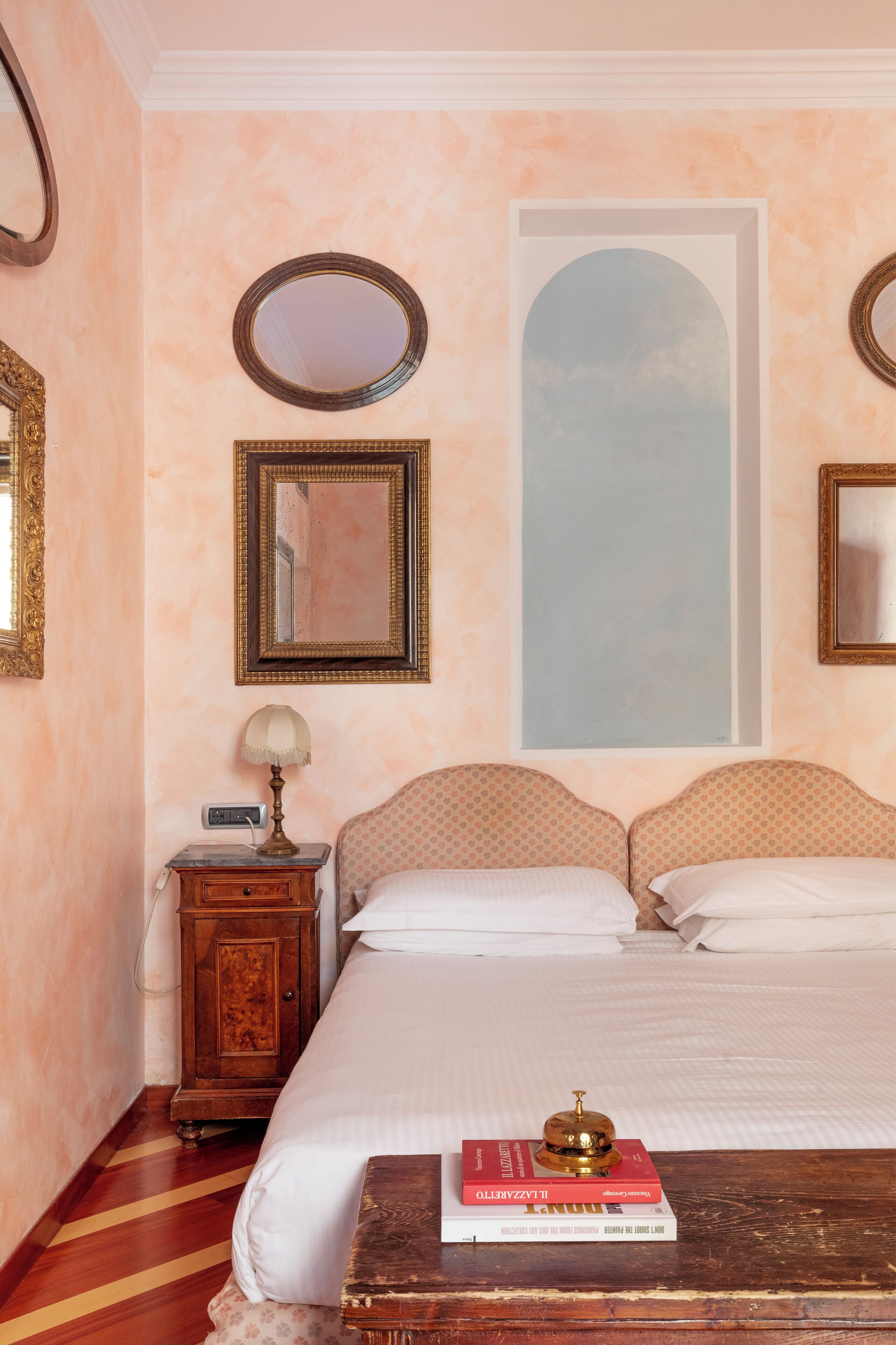 A bedroom with a bed, a nightstand, a lamp, and a mirror.