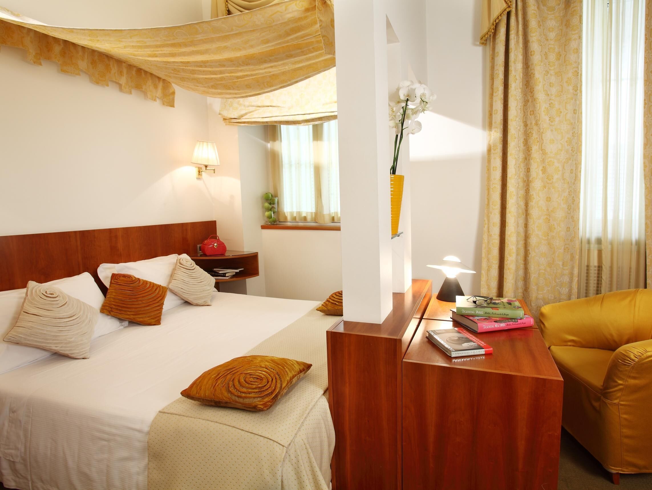 A hotel room with a bed, bedside table, lamp, and a chair.