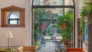 A modern hotel lobby with leather seating, a mirror, and a view of the outdoor patio. - Hotel Sanpi Milano (Milan)