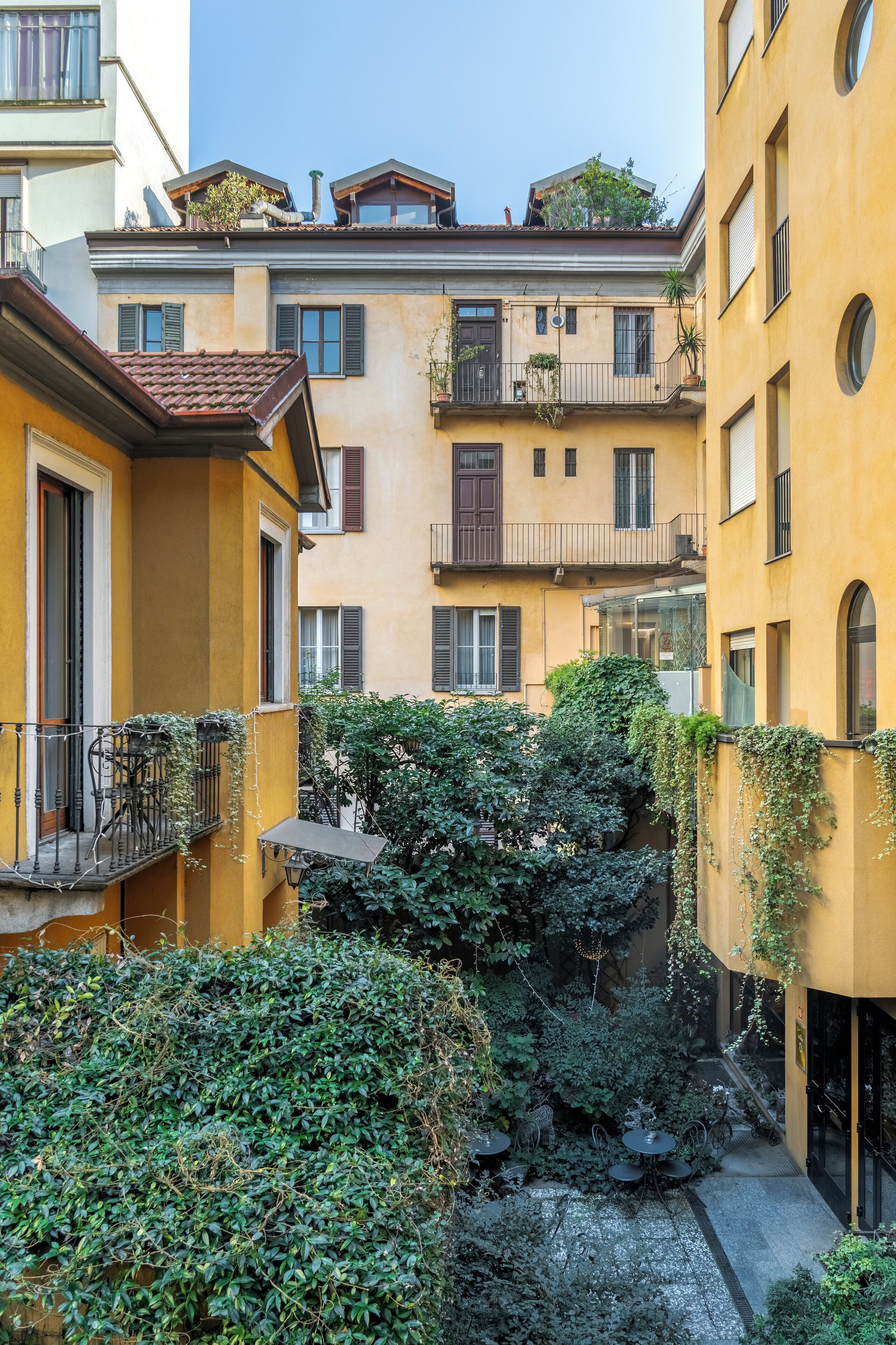 A courtyard with yellow buildings, balconies, and greenery.
