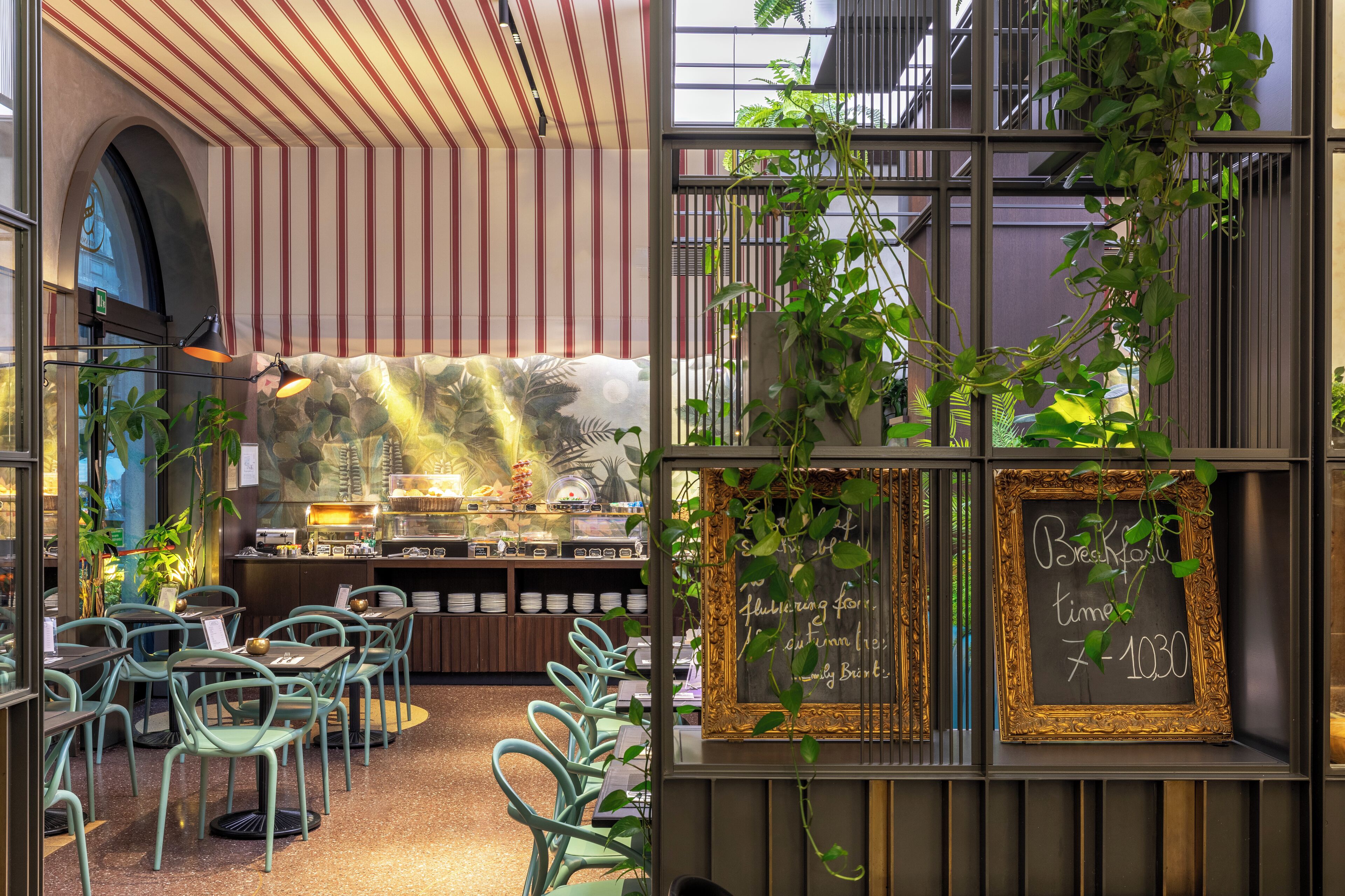 A restaurant with a rustic interior, featuring striped ceiling, green chairs, and a chalkboard menu.