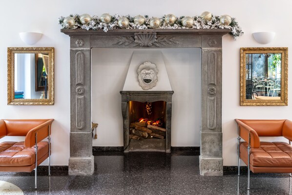 A fireplace with a decorative mantel, flanked by two leather chairs, and framed mirrors on either side. - Hotel Sanpi Milano (Milan)