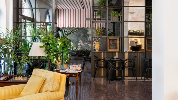 A modern interior with a sofa, dining area, and plants. - Hotel Sanpi Milano (Milan)