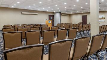 Un salón de conferencias con filas de sillas, un atril y suelo alfombrado.