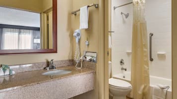 Un baño con lavamanos, espejo, secador de pelo, toallero, inodoro y cortina de ducha.