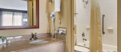 A bathroom with a sink, mirror, hairdryer, towel rack, toilet, and shower curtain.