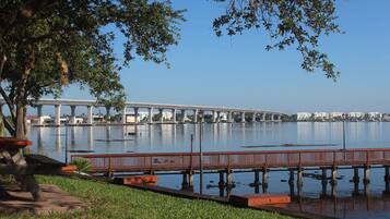 A waterfront park with a bridge, picnic tables, and a wooden walkway over the water.
