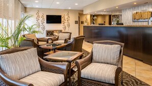 A lobby with wicker furniture, a reception desk, and a TV mounted on the wall.
