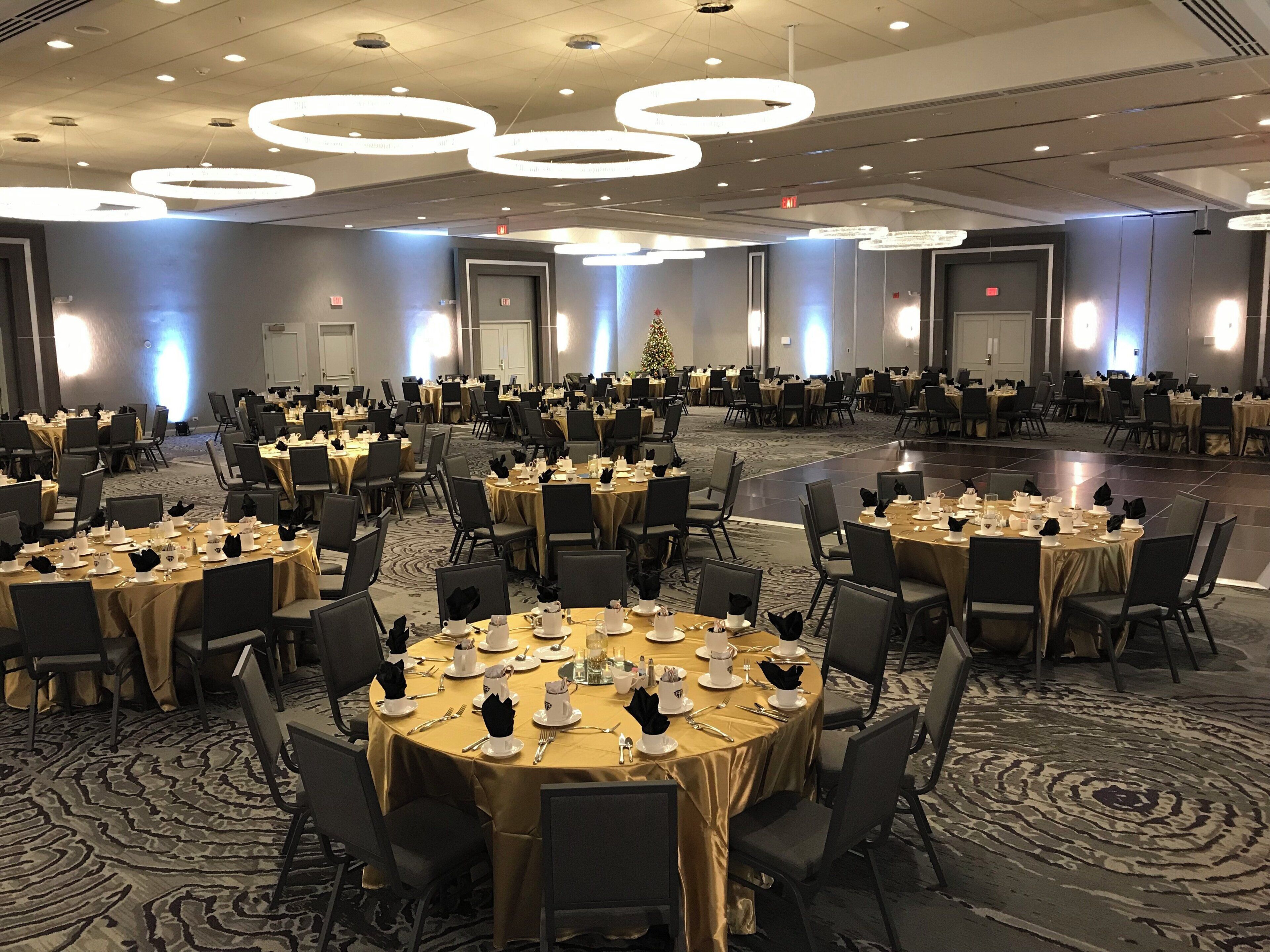 A large banquet hall with round tables set for dining, equipped with chairs and table settings.