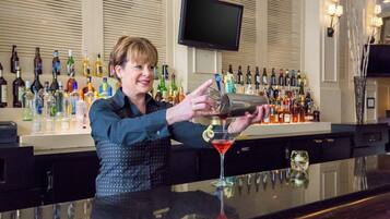 A bartender pouring a drink into a martini glass.