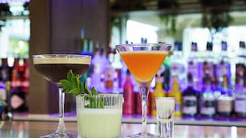 Three cocktails on a bar counter with a blurred background of bottles.