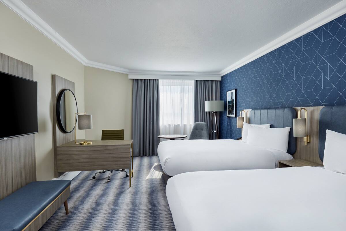 Une chambre d’hôtel avec deux lits, une télévision, un bureau et une chaise.