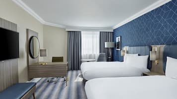 A hotel room with two beds, a TV, a desk, and a chair.