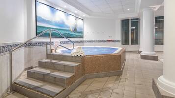 Un área de spa con hidromasaje, escalones de cerámica y un gran mural de un faro en la pared.