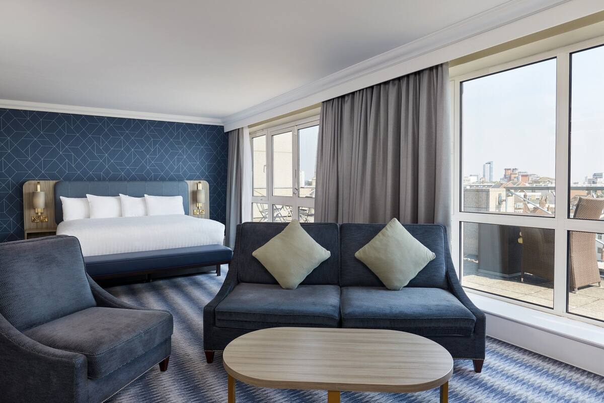 Une chambre d’hôtel avec un lit, un canapé, une chaise et une table ronde.