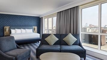 A hotel room with a bed, a sofa, a chair, and a round table.