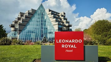 A hotel sign with the name 'LEONARDO ROYAL' in front of a modern building with a glass facade.