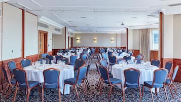 A conference room with round tables, blue chairs, and a patterned carpet.